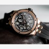 Montre sport homme avec calibre apparent, carrure et lunette en acier et PVD or rose, bracelet en caoutchouc noir.