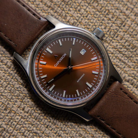 Cadran marron soleillé, index bâtons et guichet date à 3h.