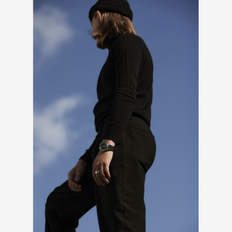 Montre noire style urbain portée avec vêtements noirs.
